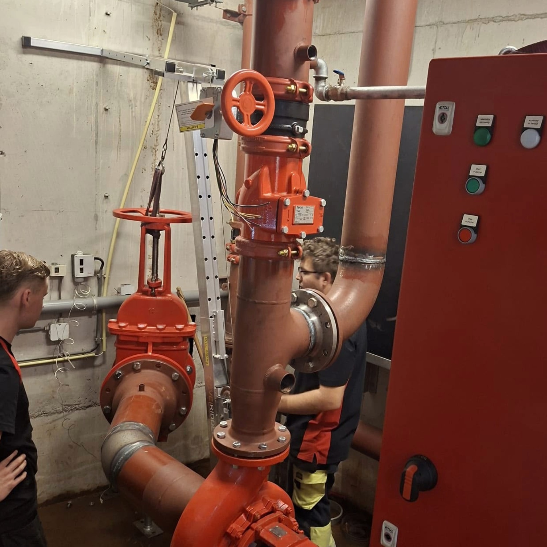 Monteur werkt aan zware installatie met afsluiter, drukmeter en leidingwerk