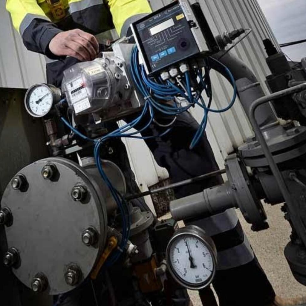 Un technicien travaille sur une installation lourde comprenant une vanne, un manomètre et des canalisations